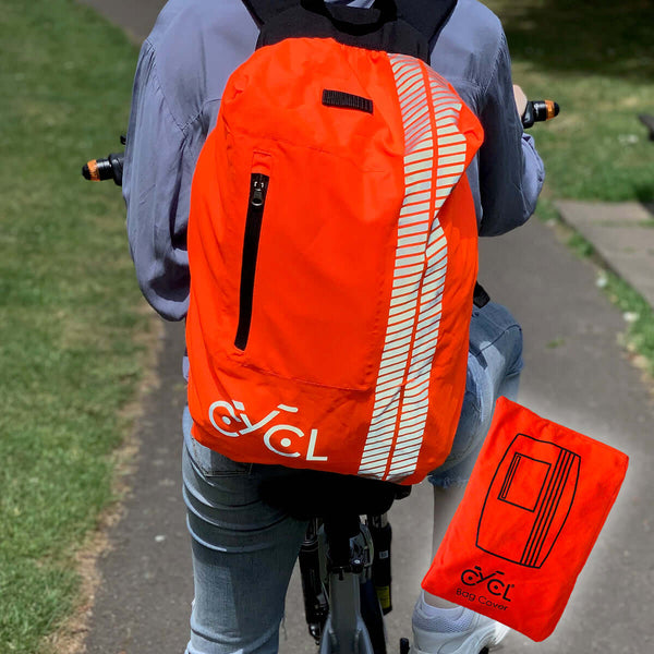 A woman wearing a CYCL high visibility backpack cover rides a bike.