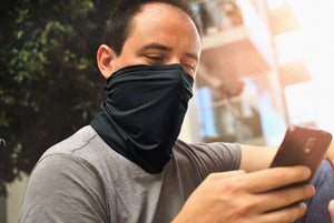 A man wearing a CYCL FaceGuard - Anti Pollution Scarf looking at his phone.