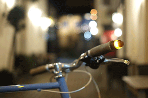 A WingLights v3 Mag by CYCL is blinking on a parked bike in a dark alleyway.